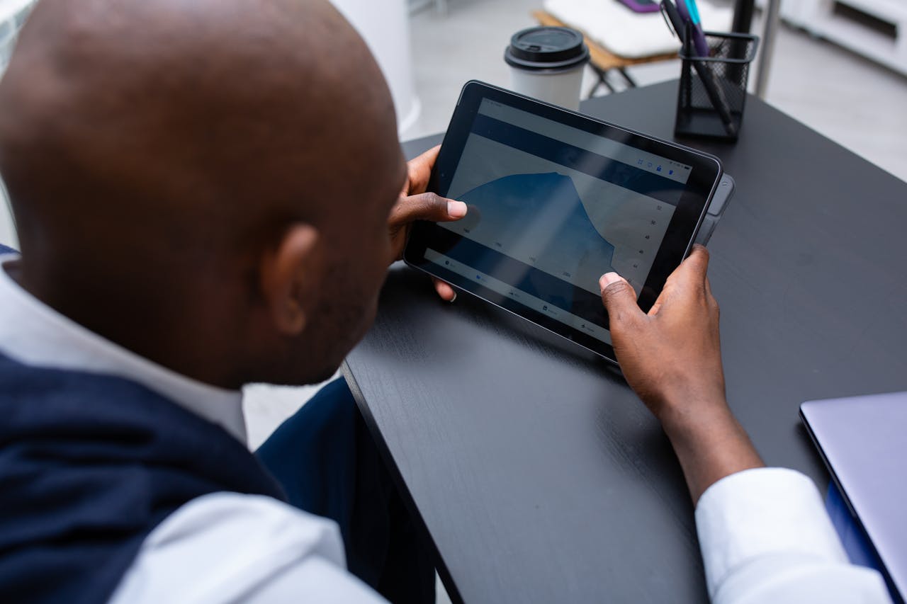Corporate professional analyzing data and graphs on digital tablet in modern office setting.